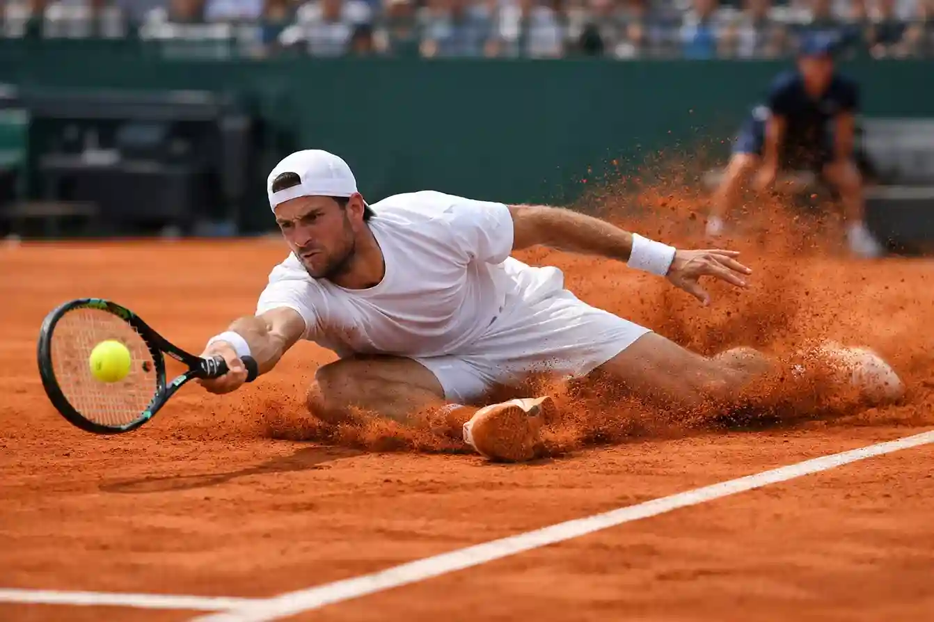 Tenista deslizándose sobre tierra batida durante un intercambio de golpes